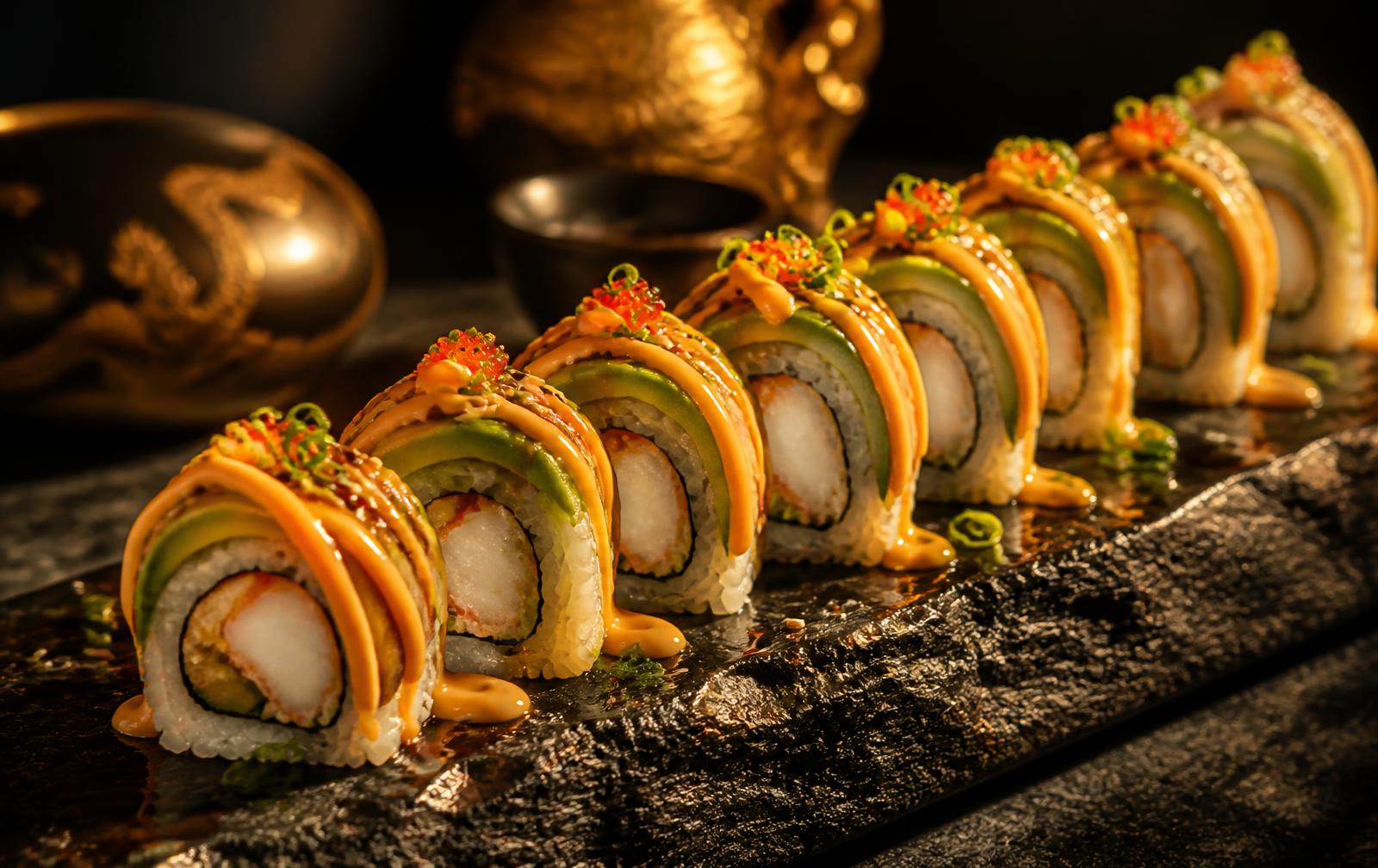 Dragon rolls met avocado en spicy mayo op een donkere plaat